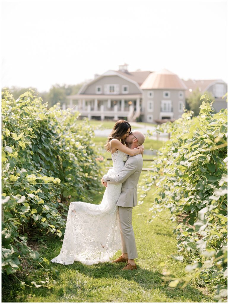 groom lifting up bride for kiss at vineyard location at Bear Brook Valley