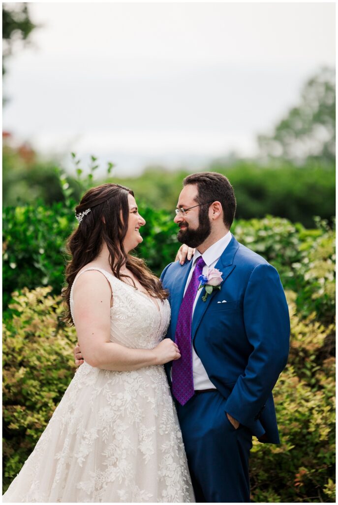 bride and groom smiling in front of green bushes at Briarcliff Manor