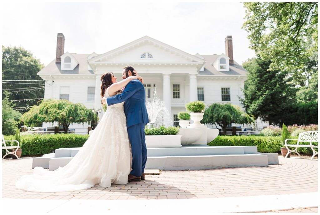 bride and groom hug in front of the fountain at Briarcliff Manor