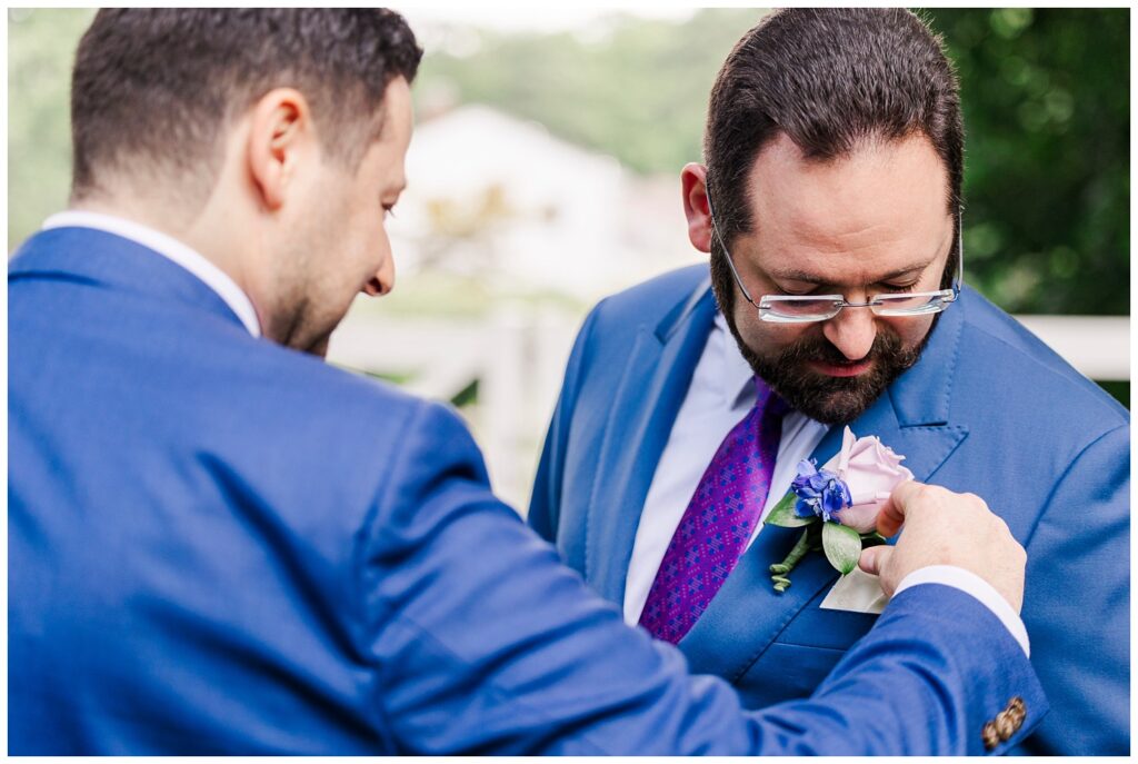 groomsman adjusting the groom's boutonniere at summer Jewish wedding 