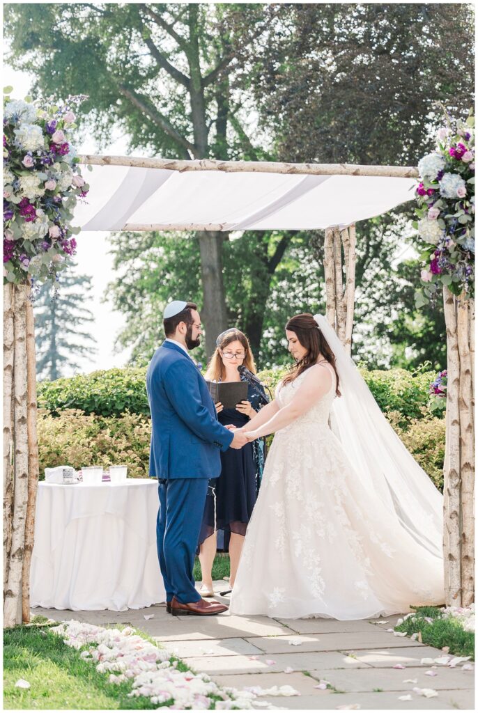bride and groom having Jewish ceremony under chuppah 