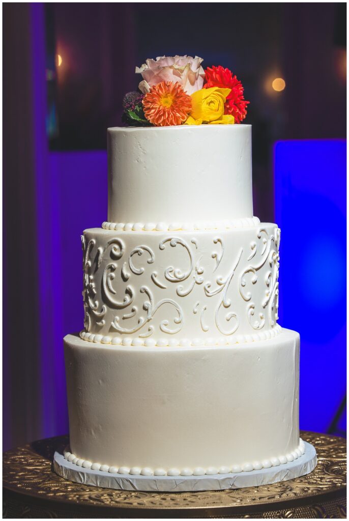 white three tiered wedding cake with flowers on top