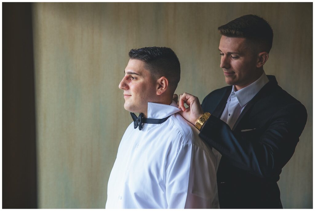 best man helping the groom put on his bowtie at The Molly Pitcher Inn