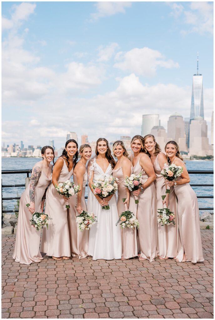 bride and bridesmaids posing by the Hudson River with the NYC skyline in the background