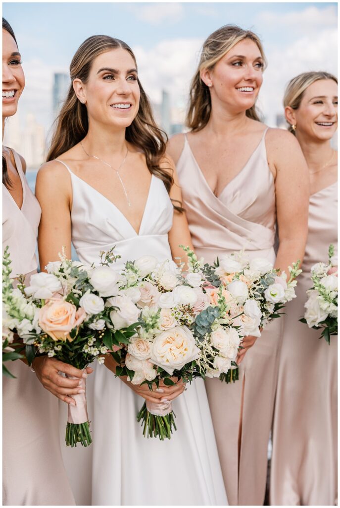 bride and bridesmaids holding their white and pink rose bouquets next to the Hudson River