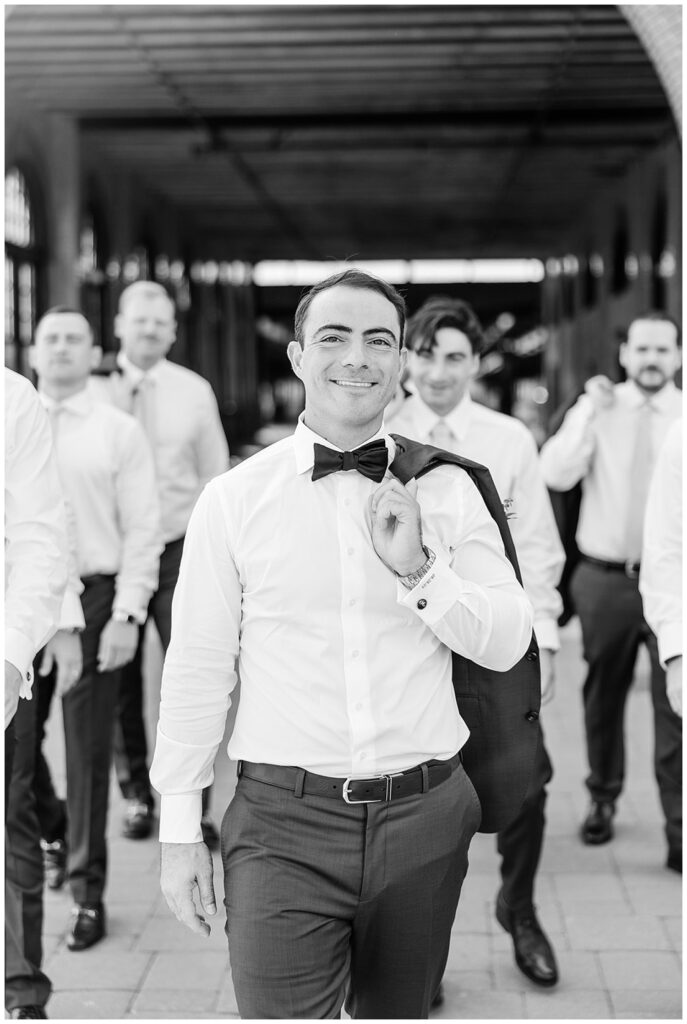 groom walking with the groomsmen while holding his jacket over his shoulder
