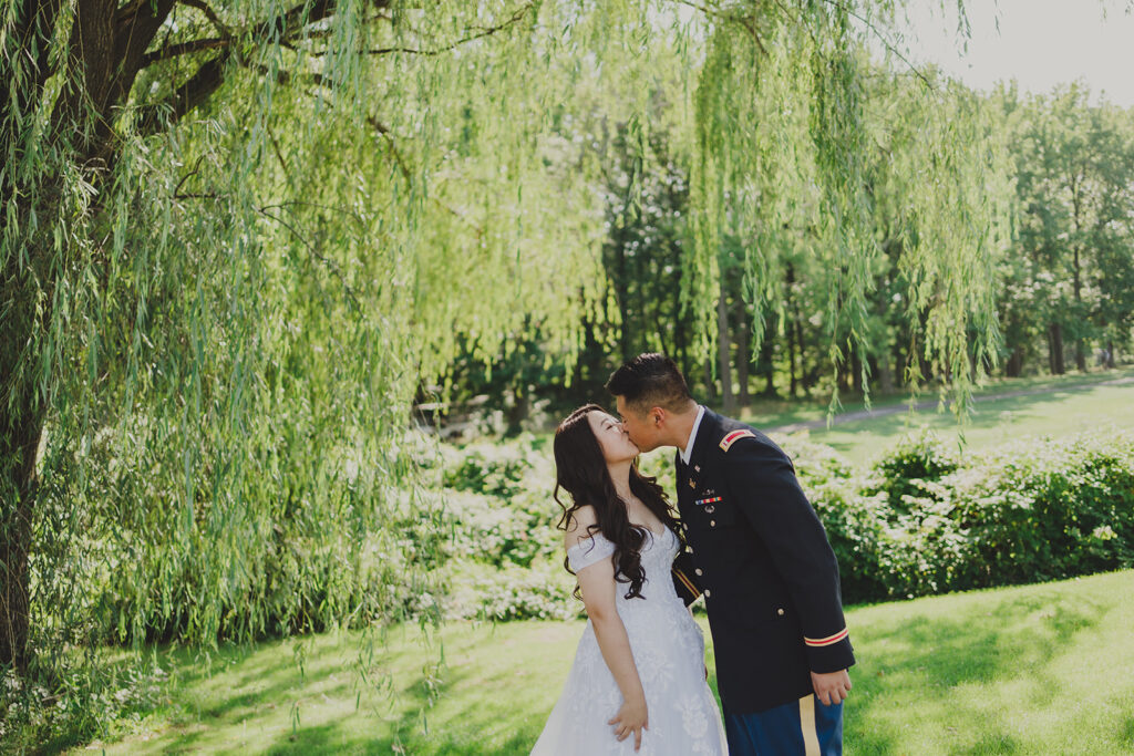 bride and groom sharing a kiss next to a willow tree at New York wedding venue