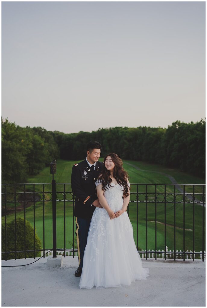 bride and groom posing for portraits on the balcony overlooking the golf course