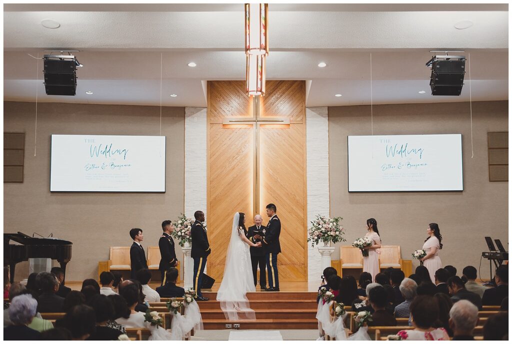 wide shot of the church ceremony while bride and groom exchange vows 