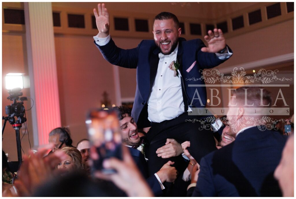 groomsmen holding up the groom on the dance floor during the wedding reception 