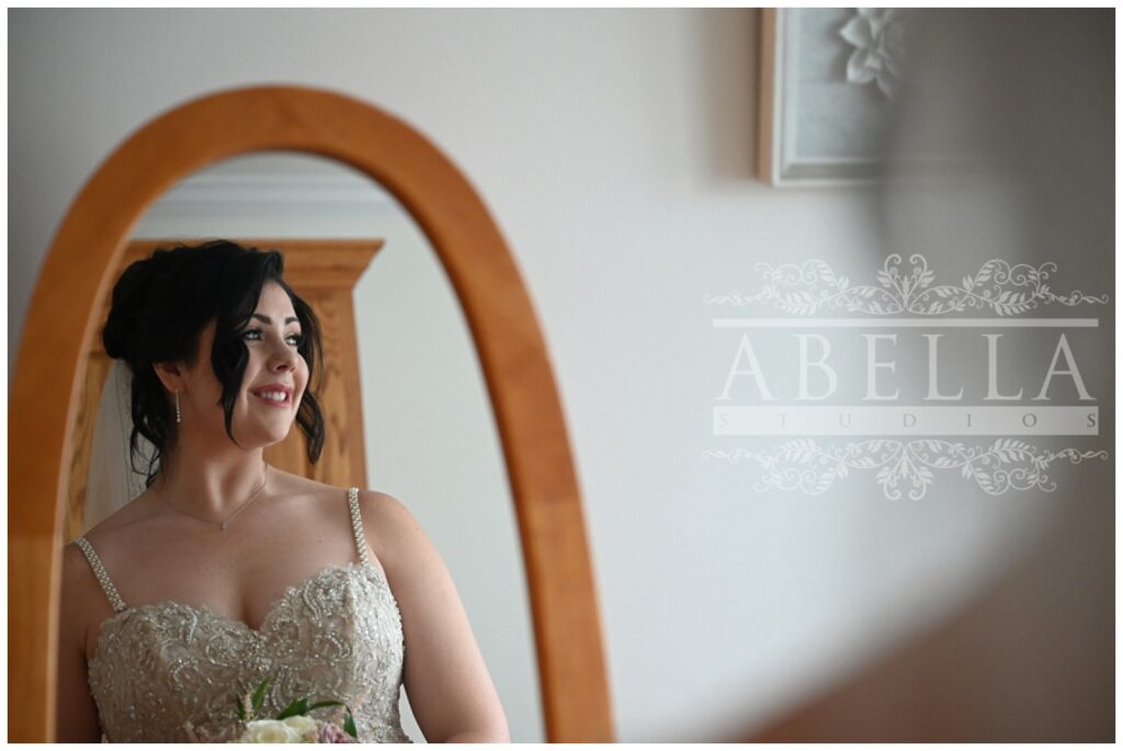 bride standing in front of a mirror and looking outside at New Jersey venue