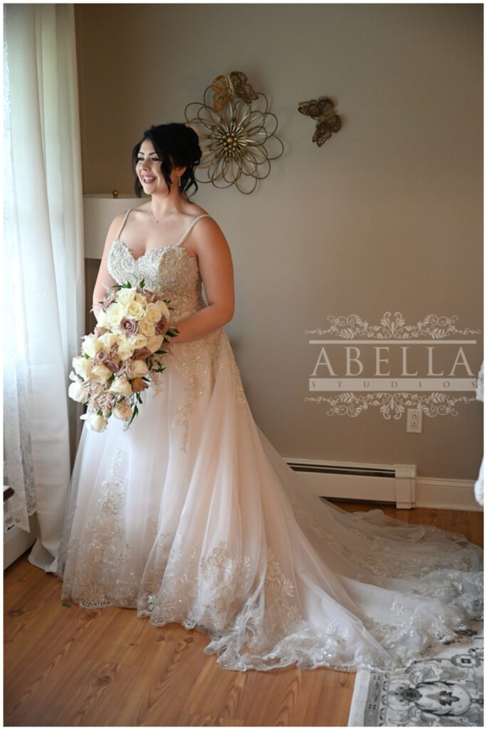 bride standing in front of the window holding her bouquet