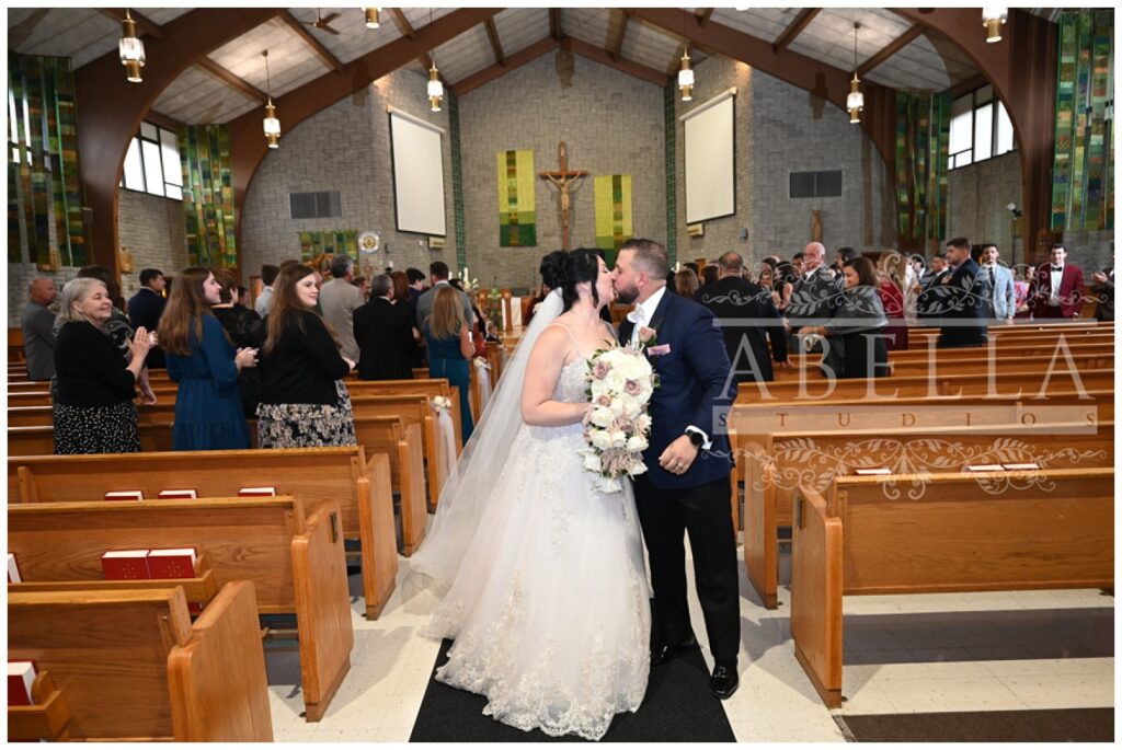 bride and groom share kiss at the end of the aisle after getting married in New Jersey
