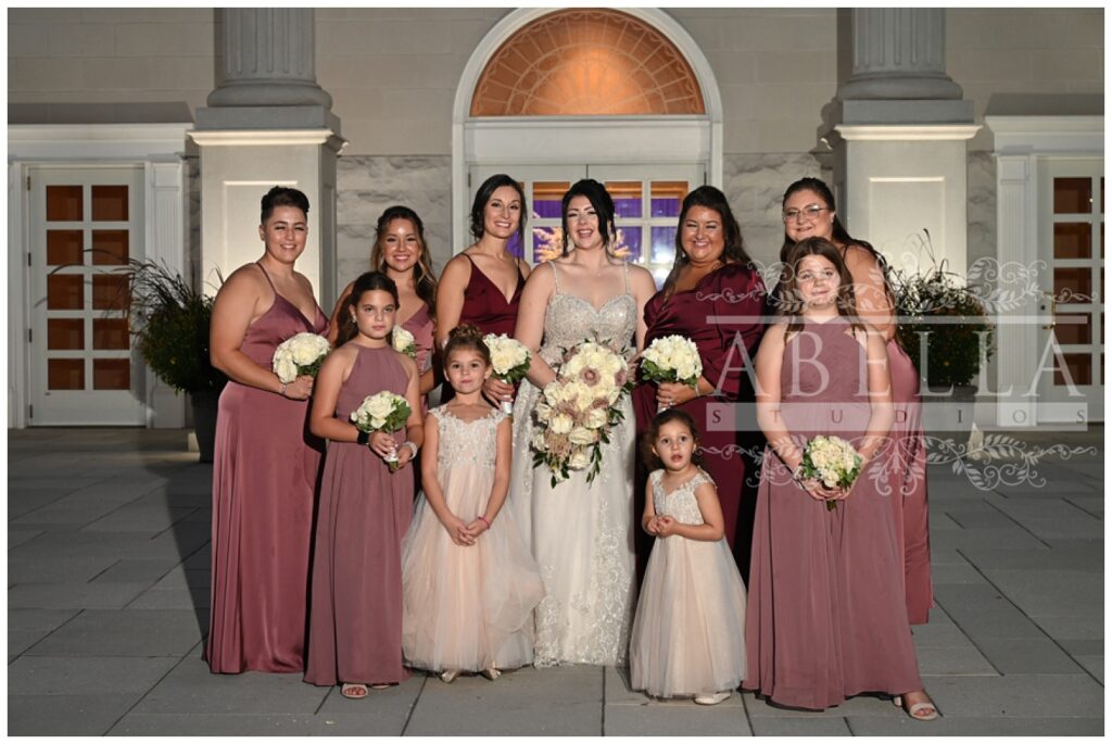 full bridal party posing outside the front entrance of the New Jersey wedding venue