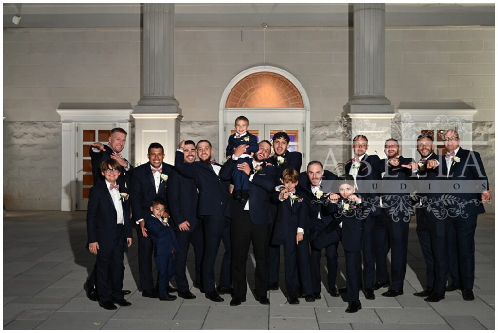 all of the groomsmen posing outside the front entrance of the New Jersey wedding venue