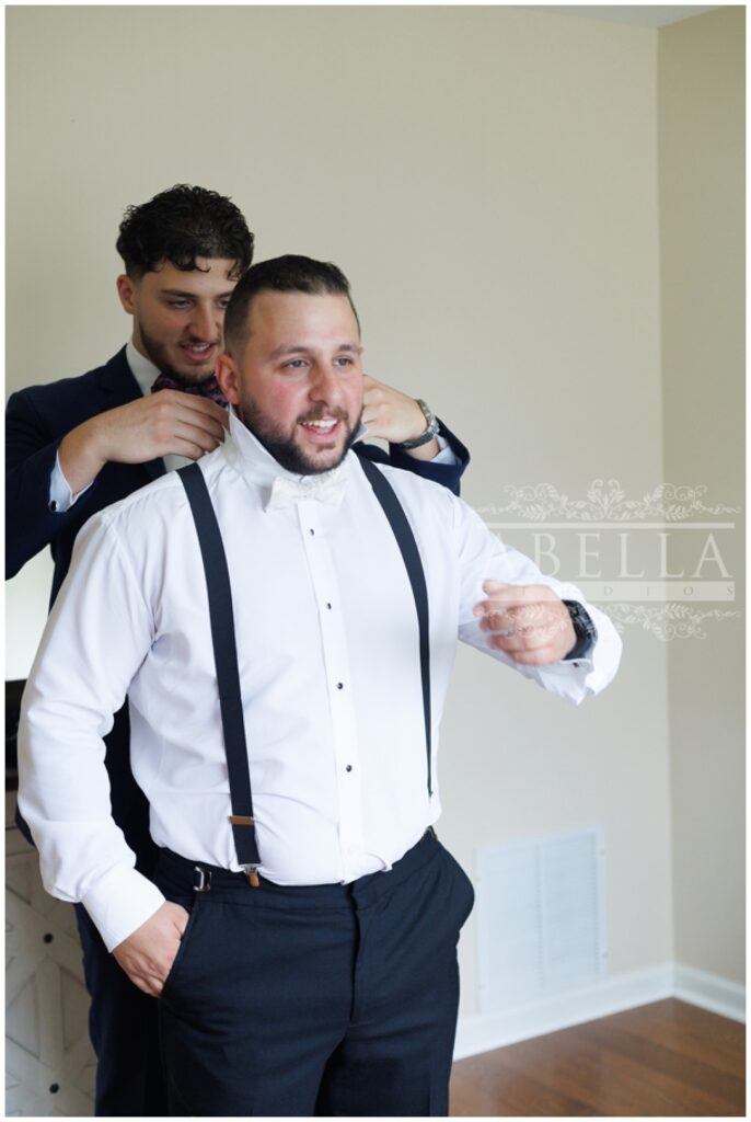 groomsman helping groom put on his tie at The Palace at Somerset Park wedding venue