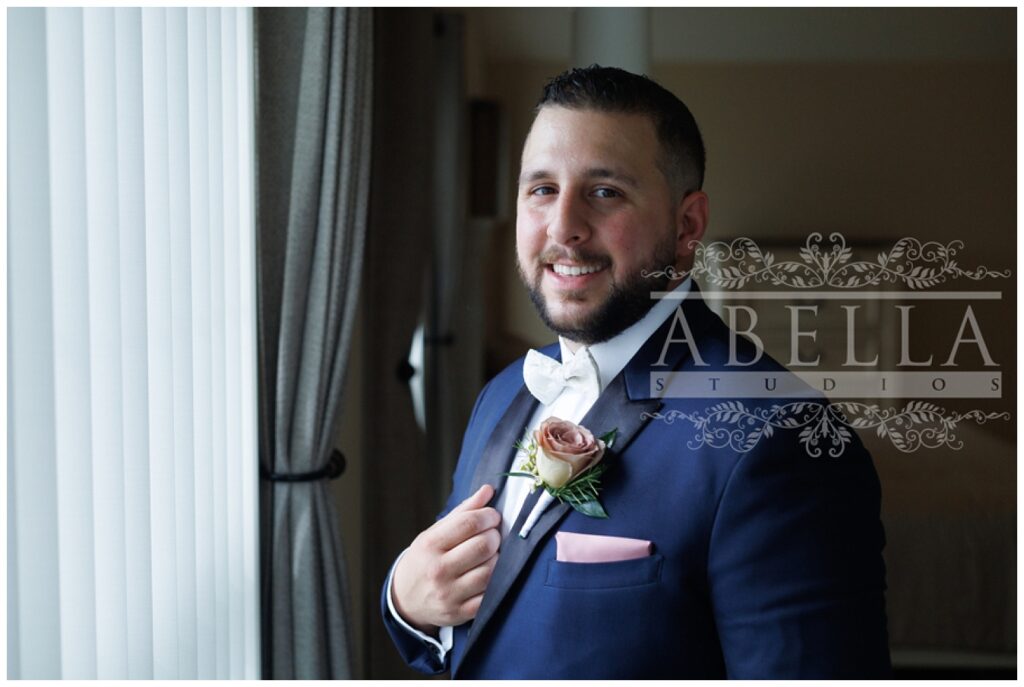 groom posing in front of the window while getting ready