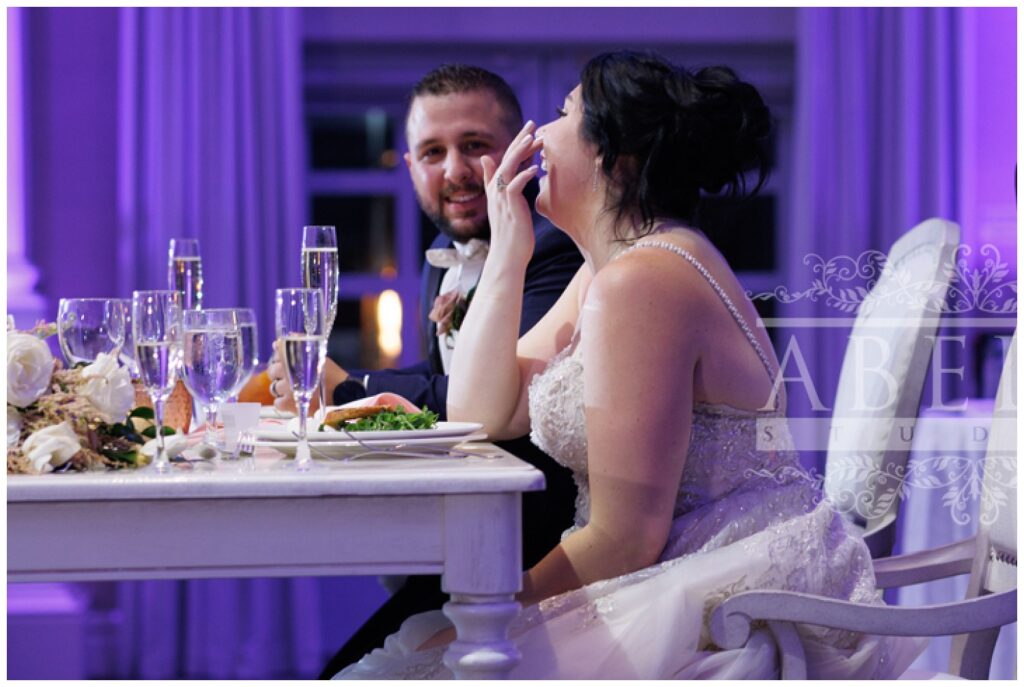 bride and groom sharing a laugh at the sweetheart table during the reception
