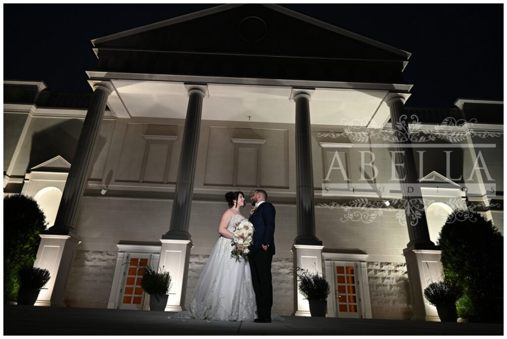 bride and groom standing outside at night at the front entrance of a New Jersey wedding venue