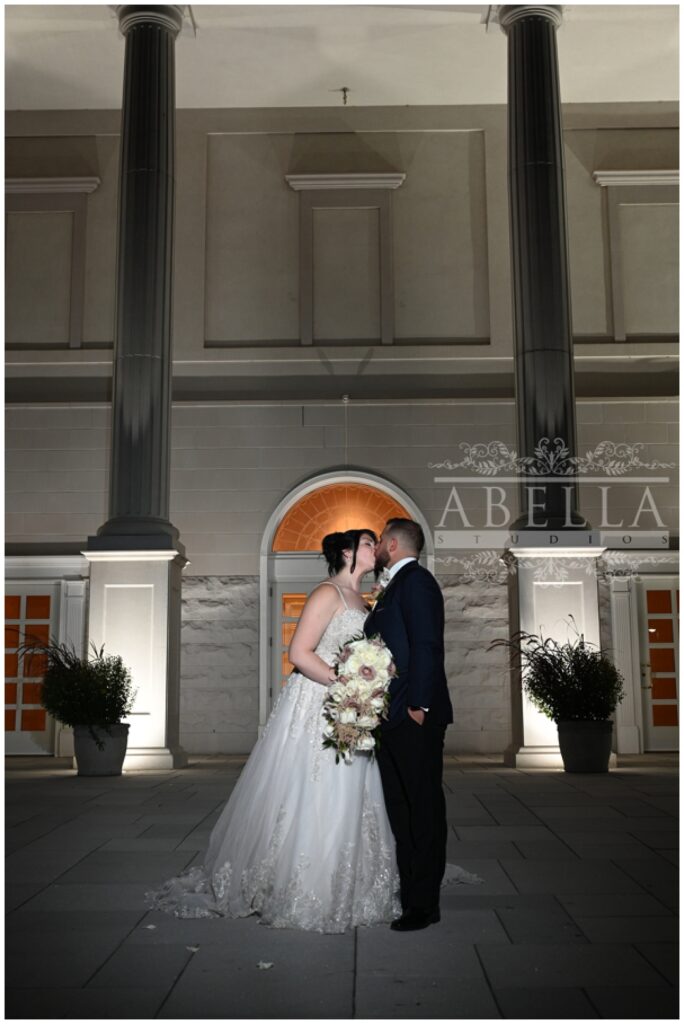 bride and groom standing outside at night at the front entrance of a New Jersey wedding venue