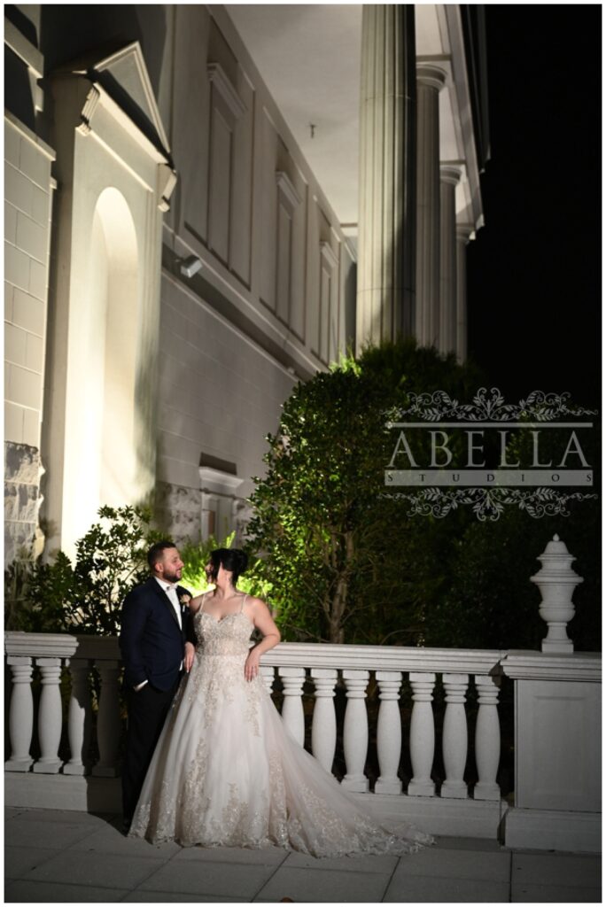 bride and groom posing against a railing at night outside the Palace at Somerset Park